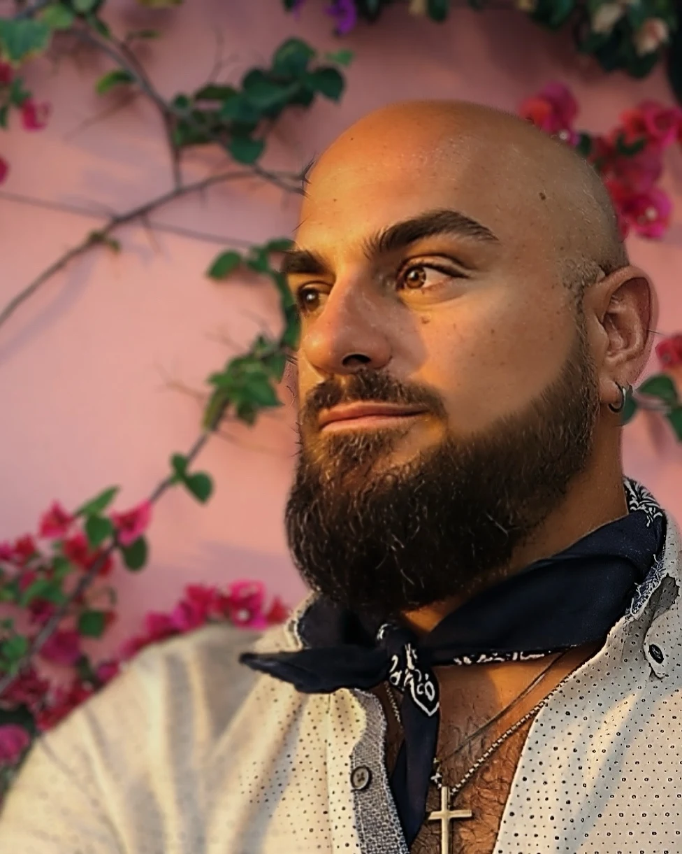 Portrait of Michael Paris, founder of The Botaniq Touch, photographed against a bougainvillea wall at golden hour.