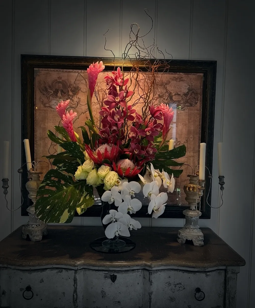 A maximalist Botaniq Touch floral arrangement with orchids, protea, roses, tropical leaves, and sculptural branches.
